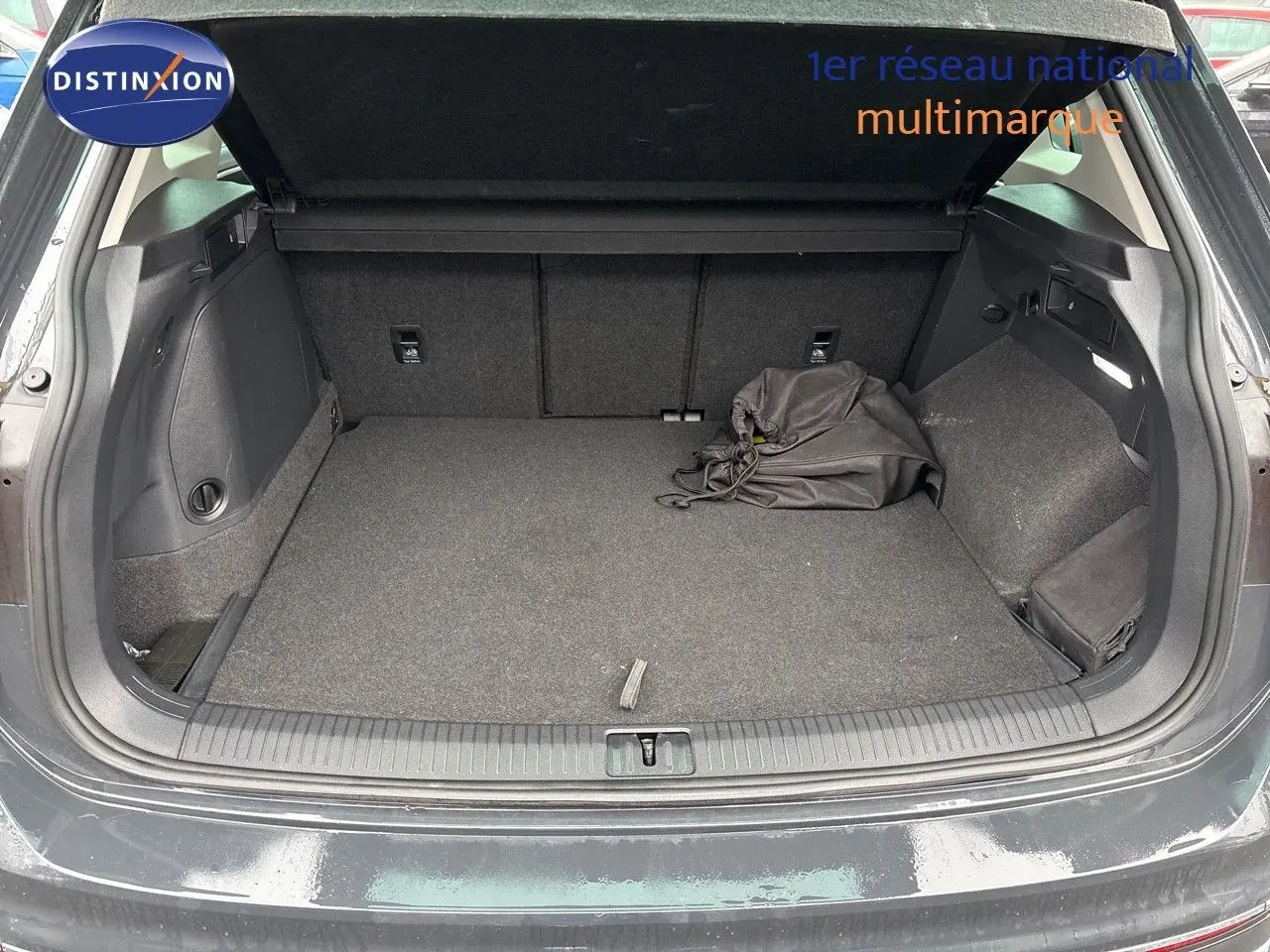 Coffre ouvert d'un Volkswagen Tiguan gris lunaire 2022, montrant un espace de chargement propre avec sac noir.