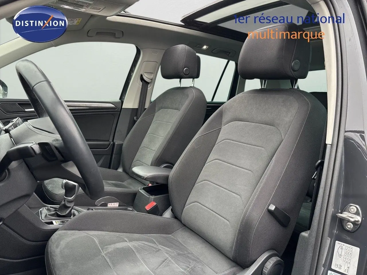 Intérieur avant du Volkswagen Tiguan gris lunaire 2022, sièges tissu gris et volant visible côté gauche.