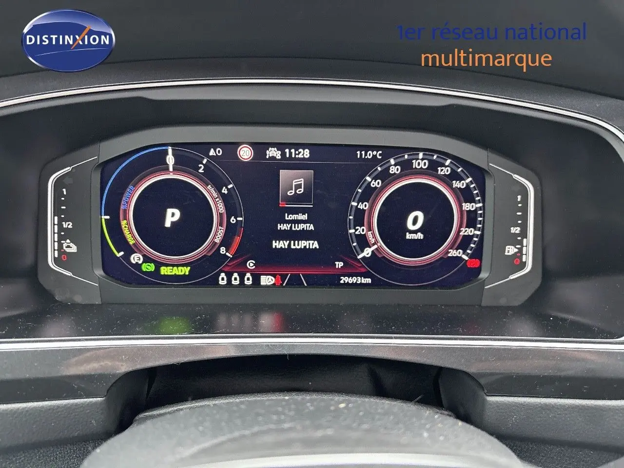 Tableau de bord numérique du Volkswagen Tiguan 1.4 E-HYBRID 245CH, affichant vitesse, mode parking et musique en cours.