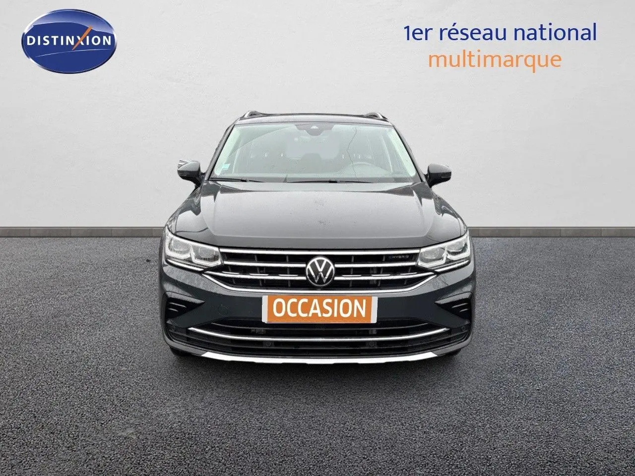 Vue frontale d'un Volkswagen Tiguan gris lunaire 2022 hybride rechargeable avec calandre chromée et logo VW visible.