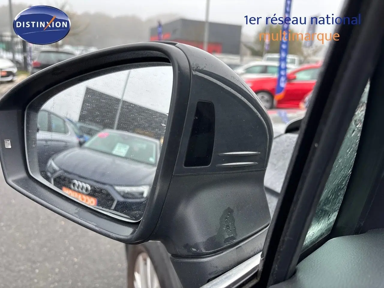 Rétroviseur extérieur gauche du Volkswagen Tiguan gris lunaire, avec reflet d'une Audi noire en arrière-plan.
