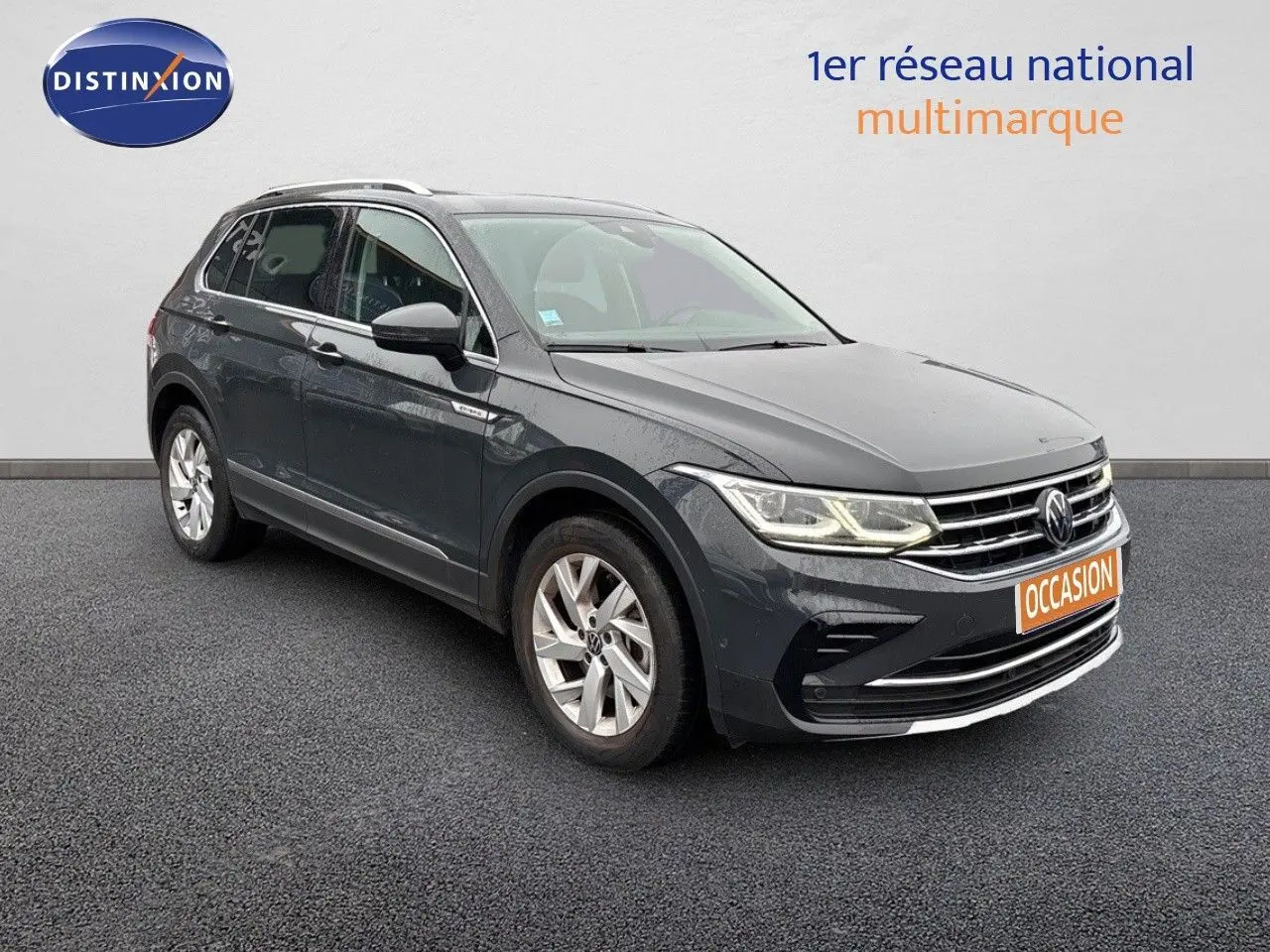 Volkswagen Tiguan 1.4 E-Hybrid gris lunaire vu en 3/4 avant droit avec phares LED allumés sur fond neutre.