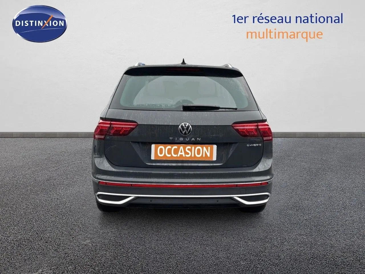 Vue arrière d'un Volkswagen Tiguan gris lunaire hybride rechargeable avec feux LED et logo distinctif visible.