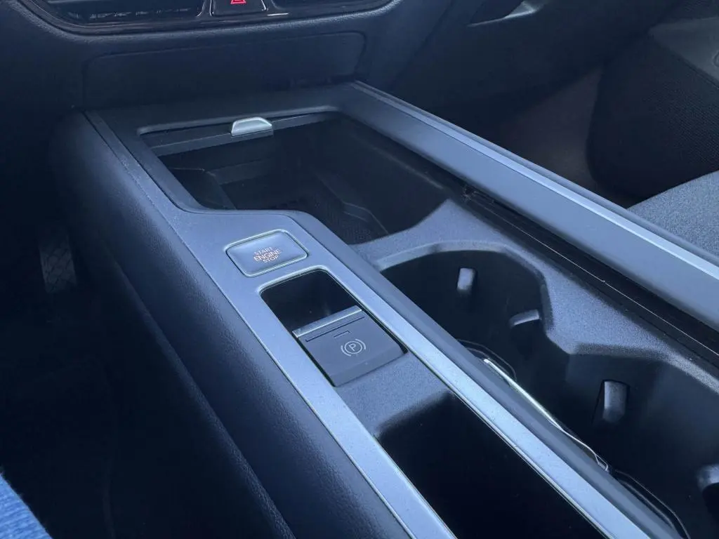Gros plan sur la console centrale noire de la Volkswagen Passat SW 2024, avec bouton start/stop et frein électronique.
