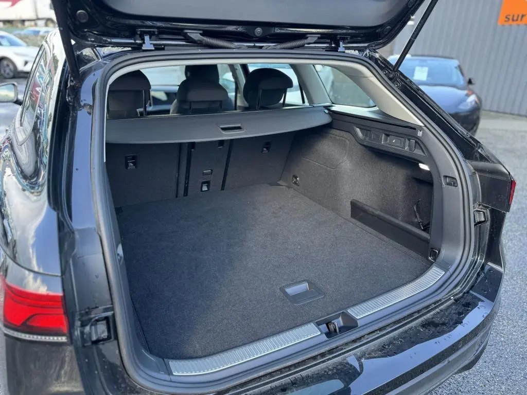 Coffre ouvert vu de l'arrière d'une Volkswagen Passat SW noire 2024, montrant un espace de chargement spacieux et bien fini.