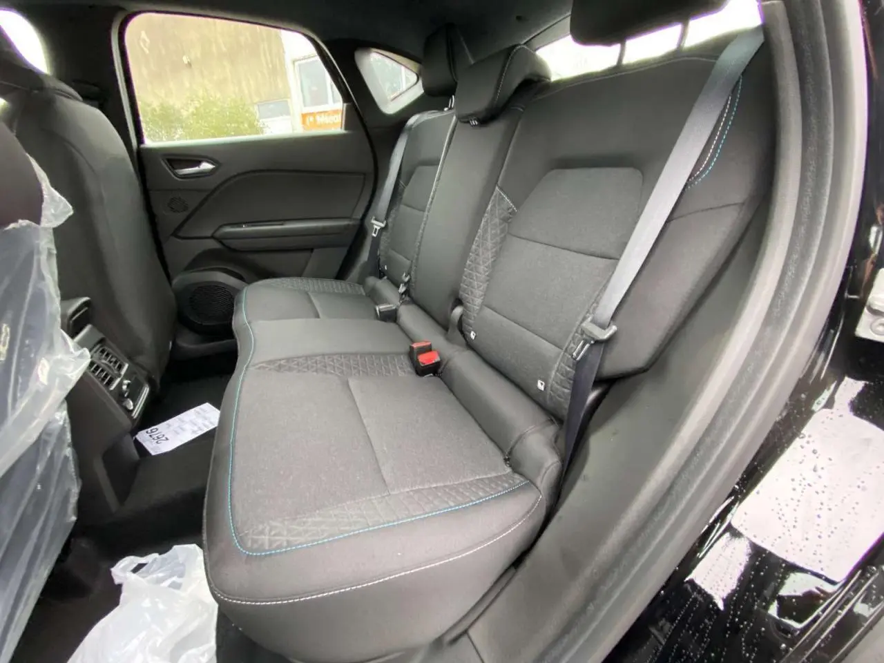Vue intérieure côté droit sur la banquette arrière noire avec surpiqûres bleues du Renault Captur 2025 Noir Étoile.