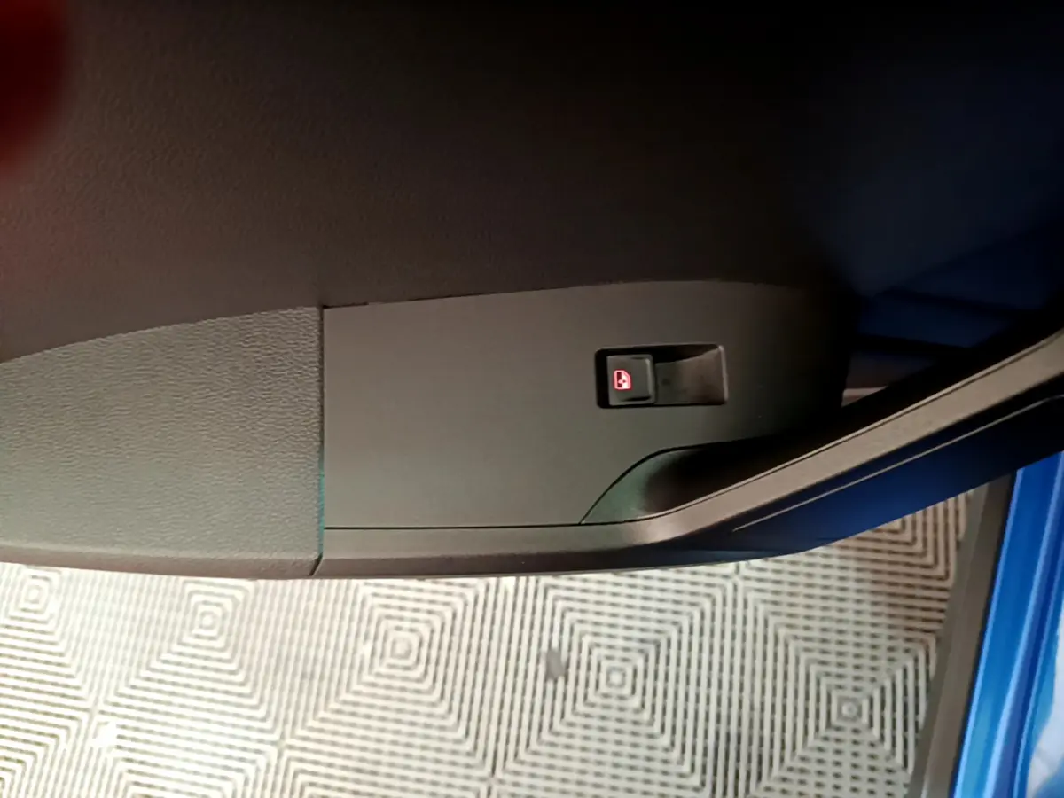 Gros plan sur le bouton de verrouillage des portes côté gauche d’une SEAT Arona bleu 2022, intérieur voiture.