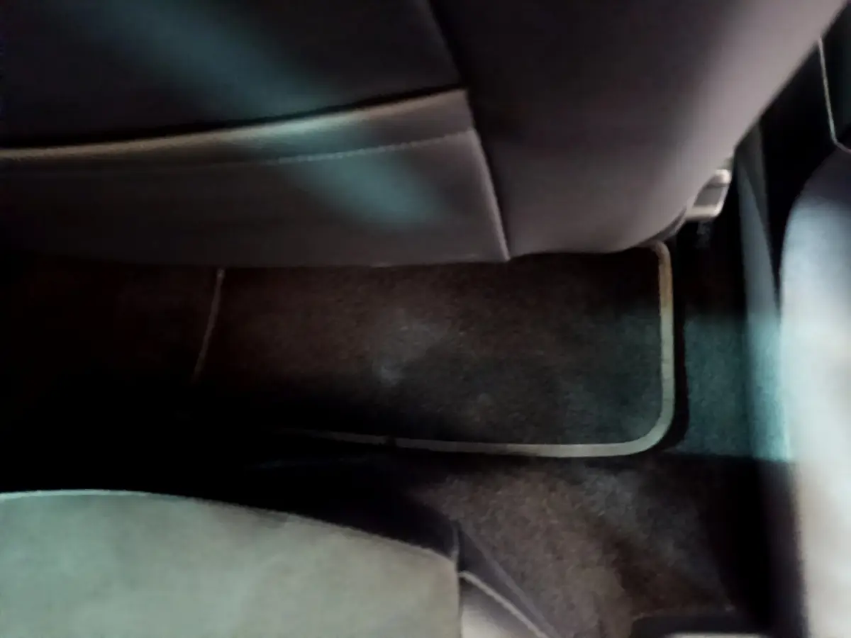 Vue intérieure en plancher arrière côté passager du SEAT Arona 2022, moquette noire et siège en cuir sombre.