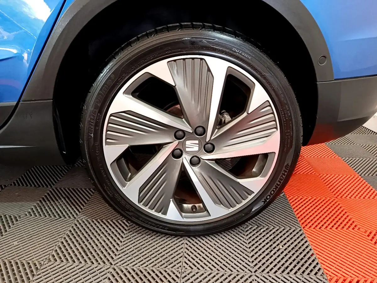 Gros plan sur la roue avant droite d'une SEAT Arona bleu 2022 avec jante alliage au design moderne.