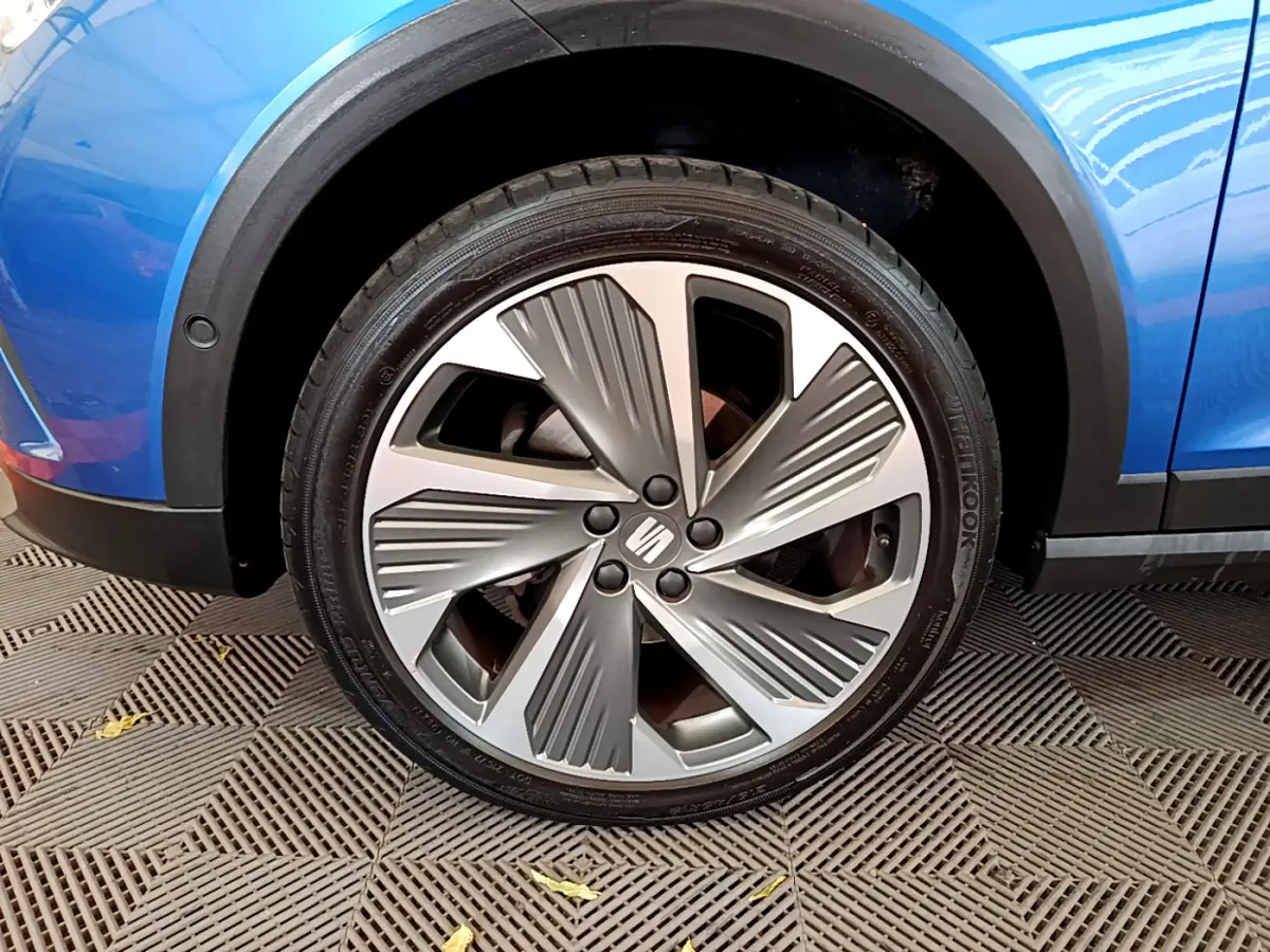 Gros plan sur la roue avant droite d’un SEAT Arona bleu 2022 avec jante alliage au design moderne.