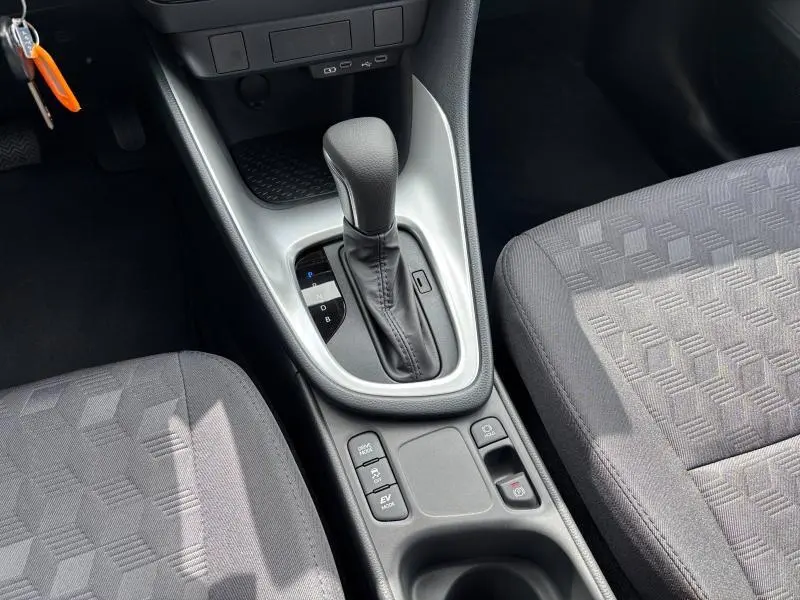 Gros plan sur la console centrale de la Toyota Yaris 116h Dynamic 2025, montrant le levier de boîte auto et les sièges gris à motifs géométriques.