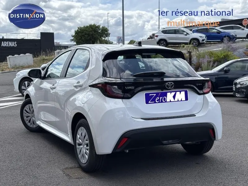 Toyota Yaris 116h Dynamic blanc vue 3/4 arrière droit, hayon noir contrastant et feux arrière LED distinctifs.