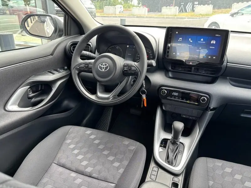 Vue intérieure côté conducteur de la Toyota Yaris 116h Dynamic 2025, avec volant multifonction et écran tactile central.