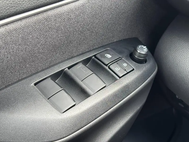 Gros plan sur les commandes de lève-vitres et réglage des rétroviseurs côté conducteur de la Toyota Yaris 116h Dynamic blanche 2025.