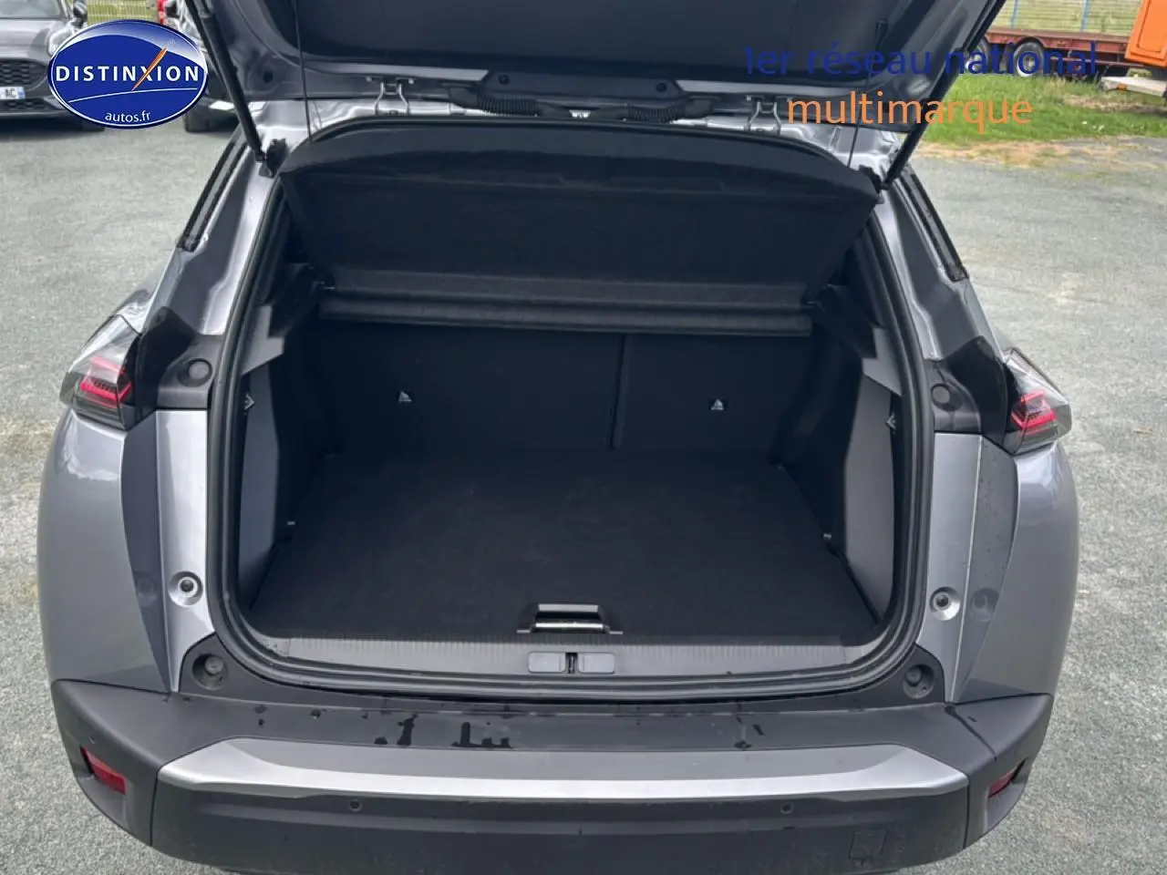 Coffre ouvert vu de l'arrière d'un Peugeot 2008 gris artense avec feux arrière à LED visibles.