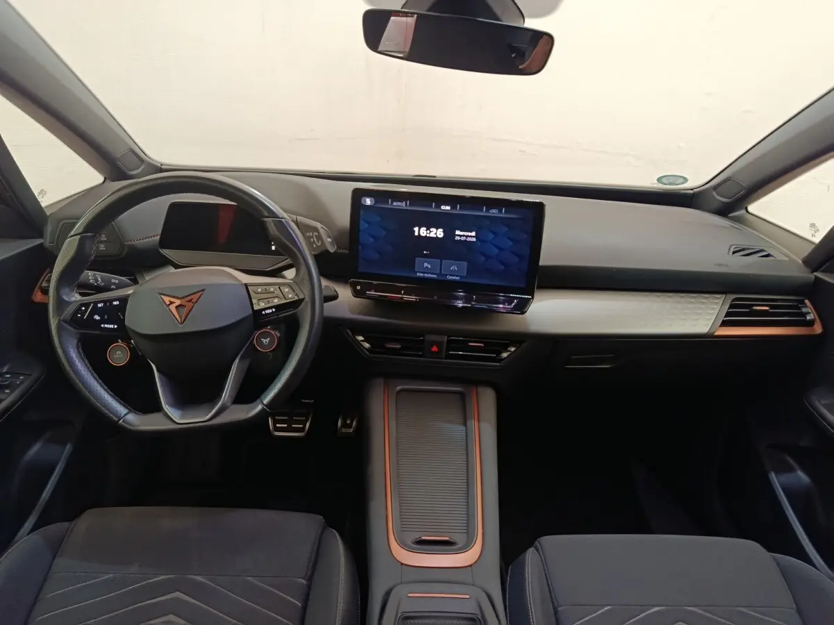 Vue intérieure avant du tableau de bord et volant cuir noir avec logo CUPRA, écran tactile central 12 pouces, détails cuivre.