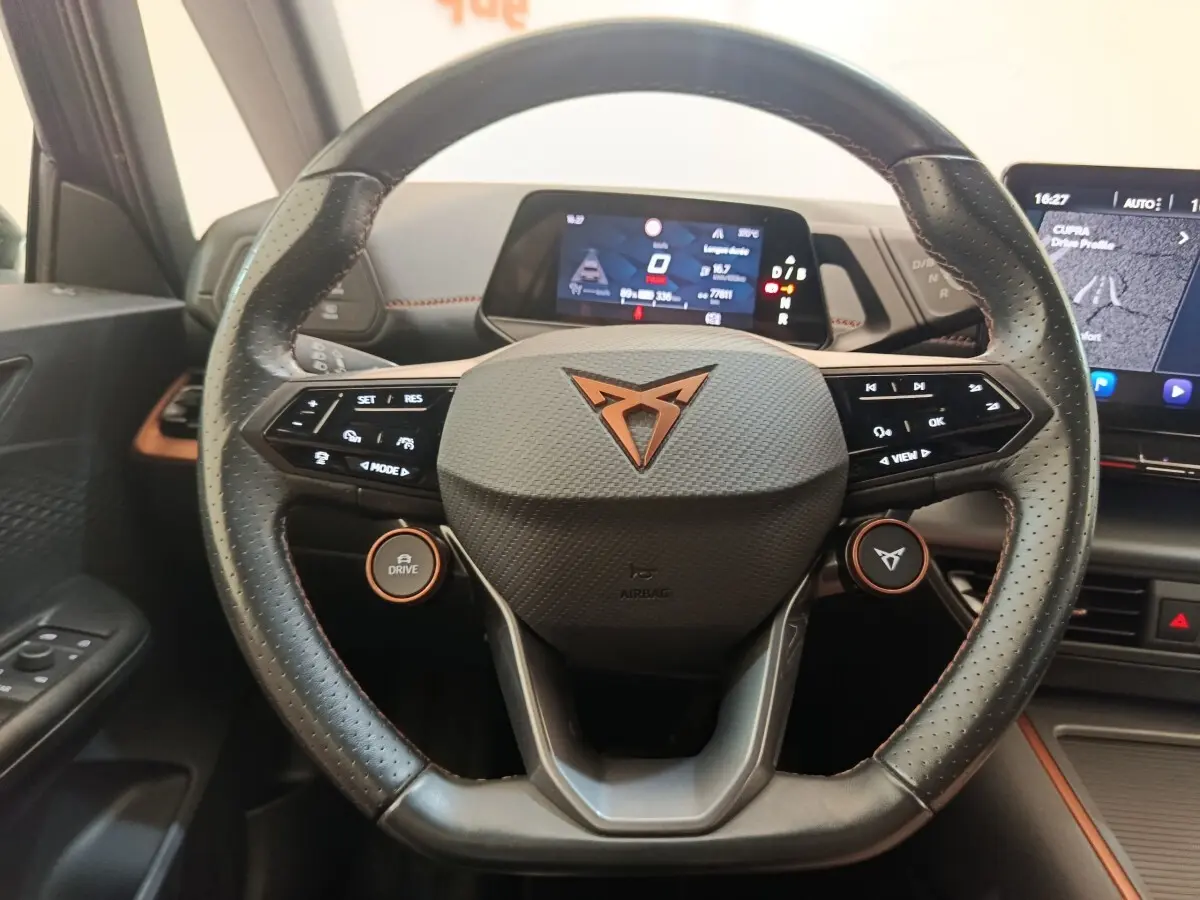 Vue rapprochée du volant cuir noir avec logo CUPRA orange du tableau de bord du CUPRA Born gris foncé 2023 électrique.
