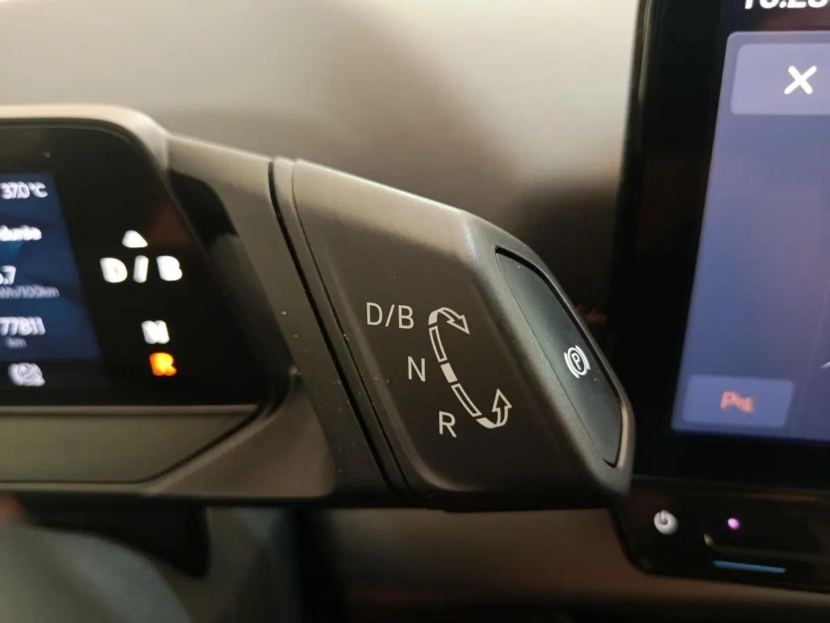 Gros plan sur la commande de boîte automatique D/B, N, R avec bouton frein à main électronique dans un CUPRA BORN gris foncé.