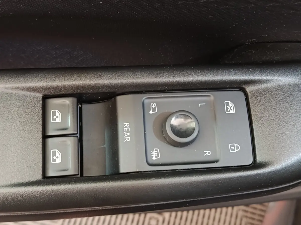 Gros plan sur les commandes de réglage des rétroviseurs et des vitres électriques côté conducteur d'une CUPRA Born gris foncé.
