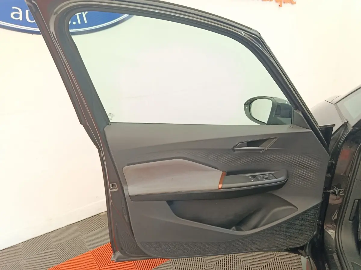 Vue intérieure de la porte avant gauche gris foncé de la CUPRA BORN 230ch avec garniture tissu et commandes électriques.
