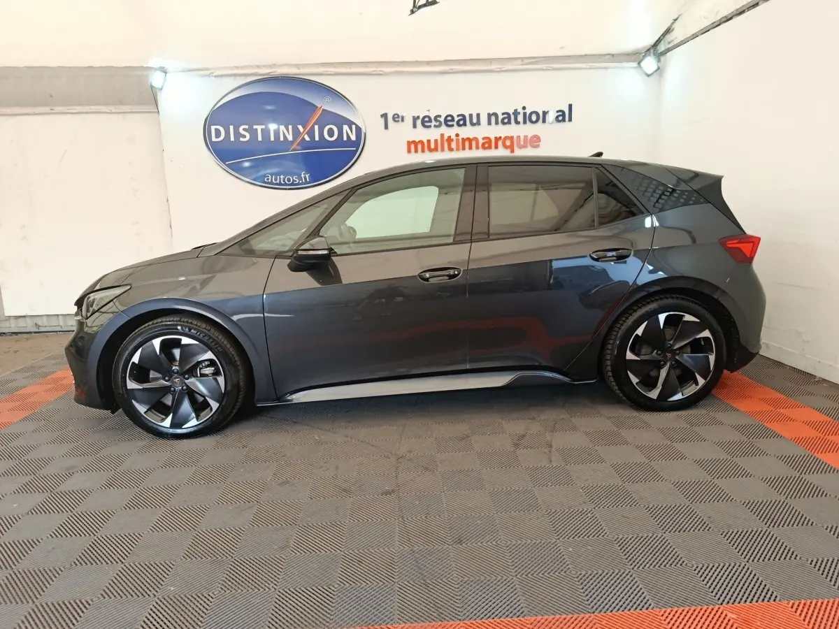 Vue de profil côté gauche d'une CUPRA BORN 230ch gris foncé, avec jantes noires et détails sportifs visibles.