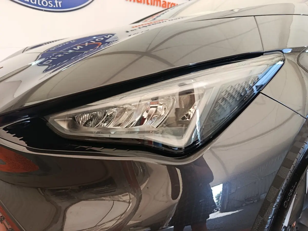 Gros plan sur le phare avant droit du CUPRA BORN gris foncé 2023, soulignant ses lignes anguleuses et détails LED.