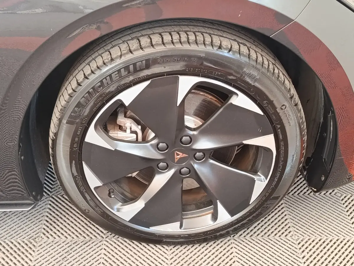 Gros plan sur la roue avant droite gris foncé du CUPRA BORN 230ch avec jante alliage bicolore et logo CUPRA central.
