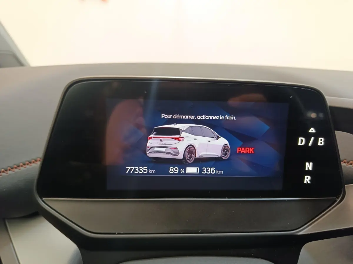 Écran digital du tableau de bord montrant une illustration arrière blanche du CUPRA Born avec autonomie et kilométrage.