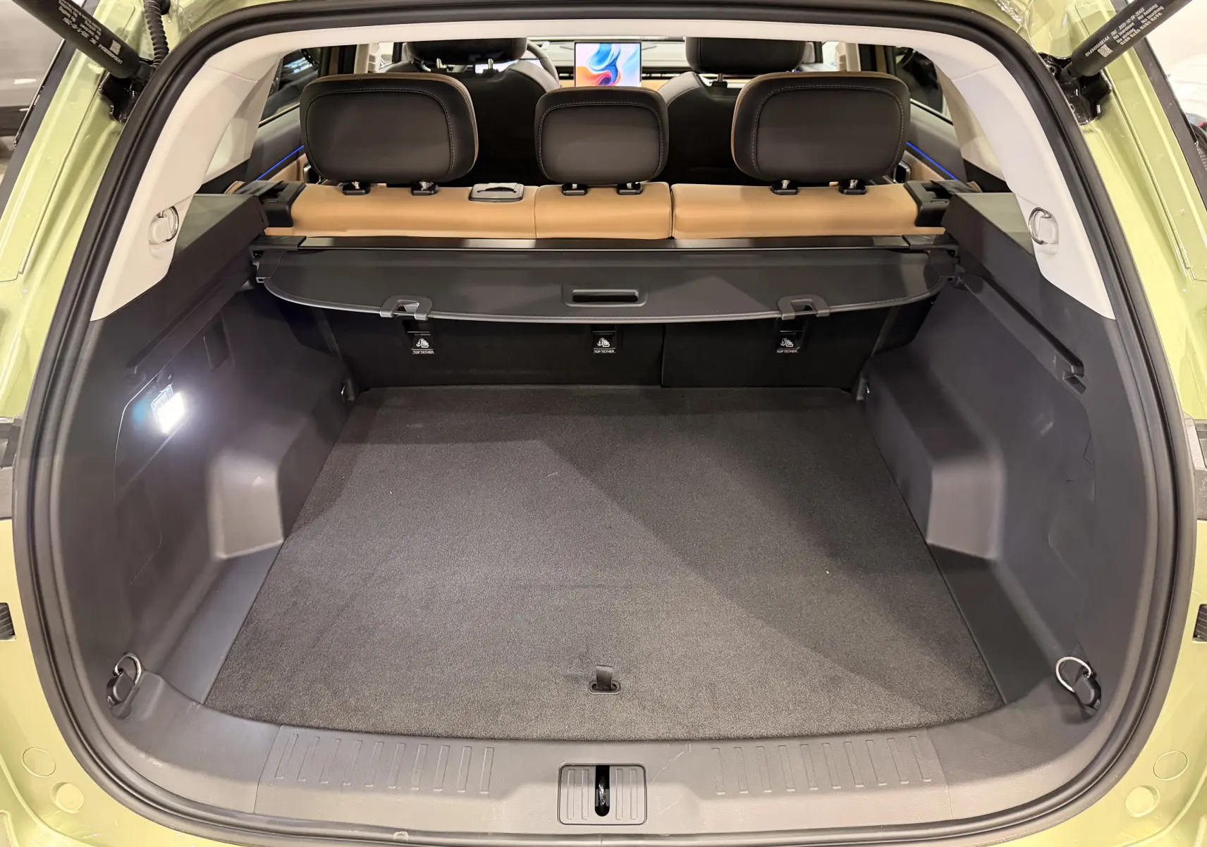Coffre ouvert vu de l'arrière du JAECOO J7 gris olive, avec banquette arrière cuir brun et cache-bagages déployé.