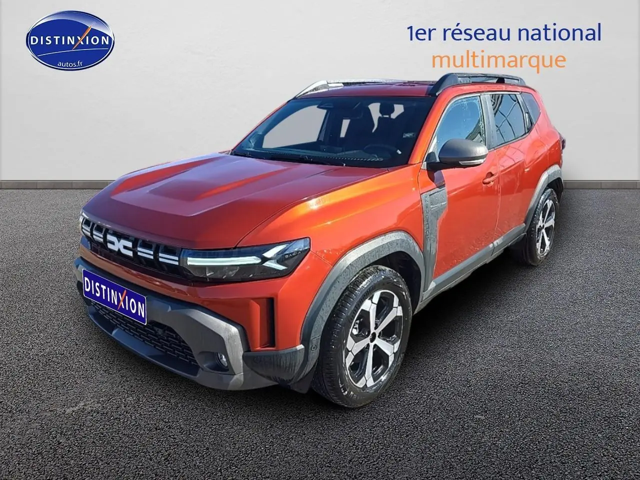 Dacia Duster 2025 brun terracotta en 3/4 avant droit avec barres de toit et jantes alu distinctives
