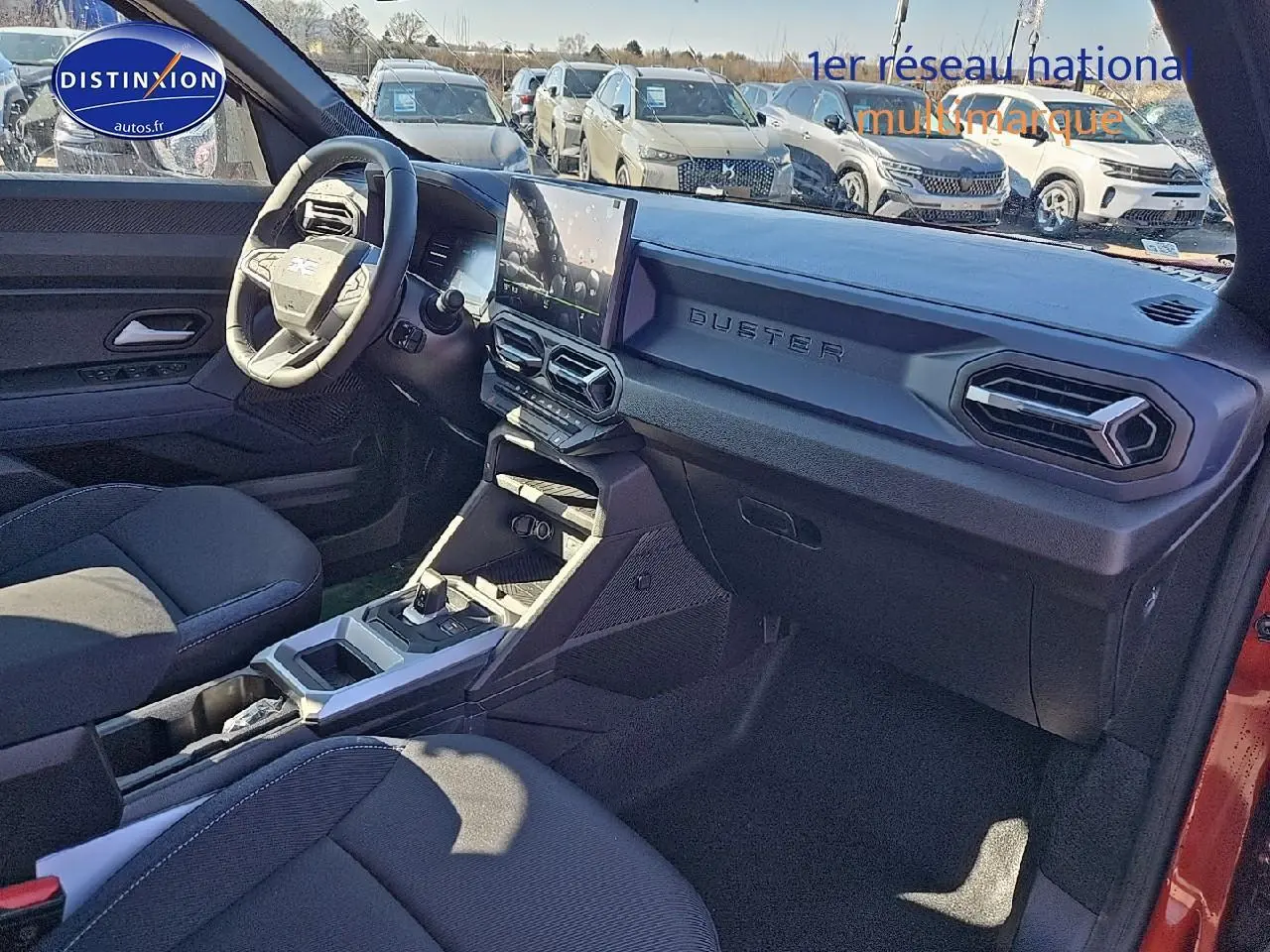 Intérieur avant droit du Dacia Duster 2025 avec tableau de bord noir et écran tactile central visible.