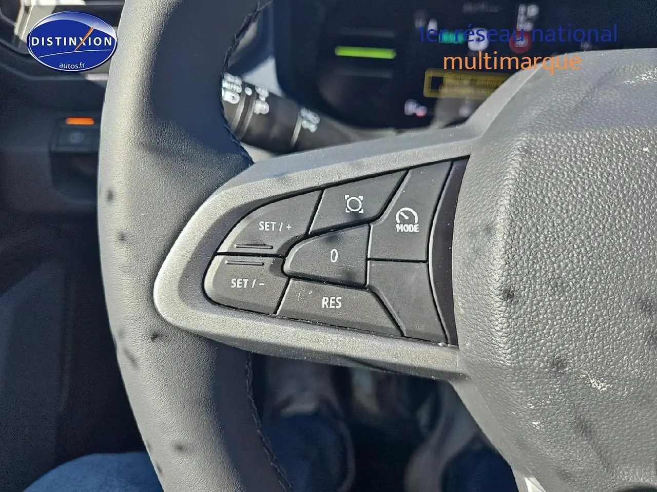 Gros plan sur les commandes du volant côté gauche du Dacia Duster brun terracotta 2025, mode cruise control visible.
