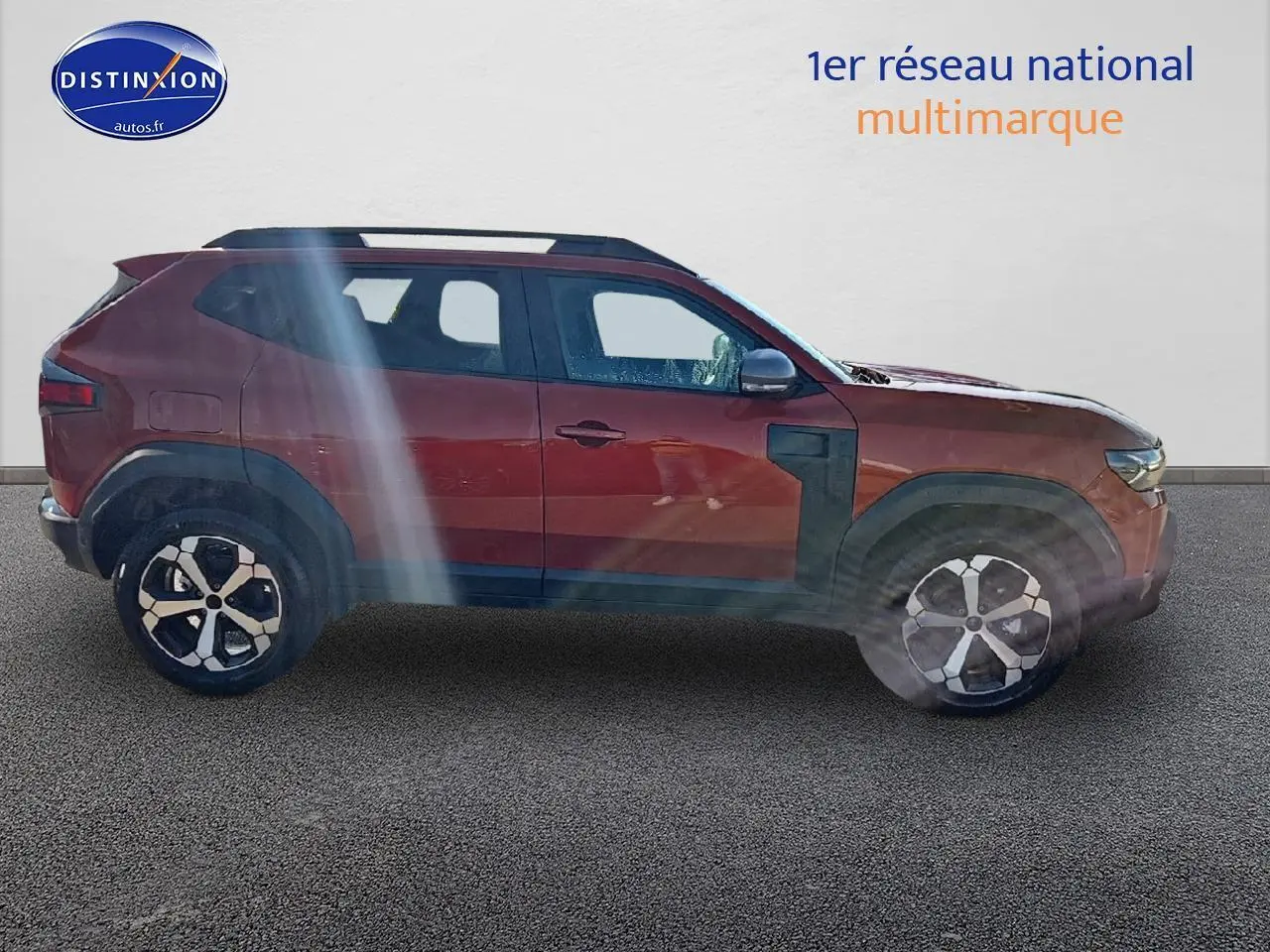 Profil droit du Dacia Duster 2025 brun terracotta avec jantes alu et barres de toit noires visibles