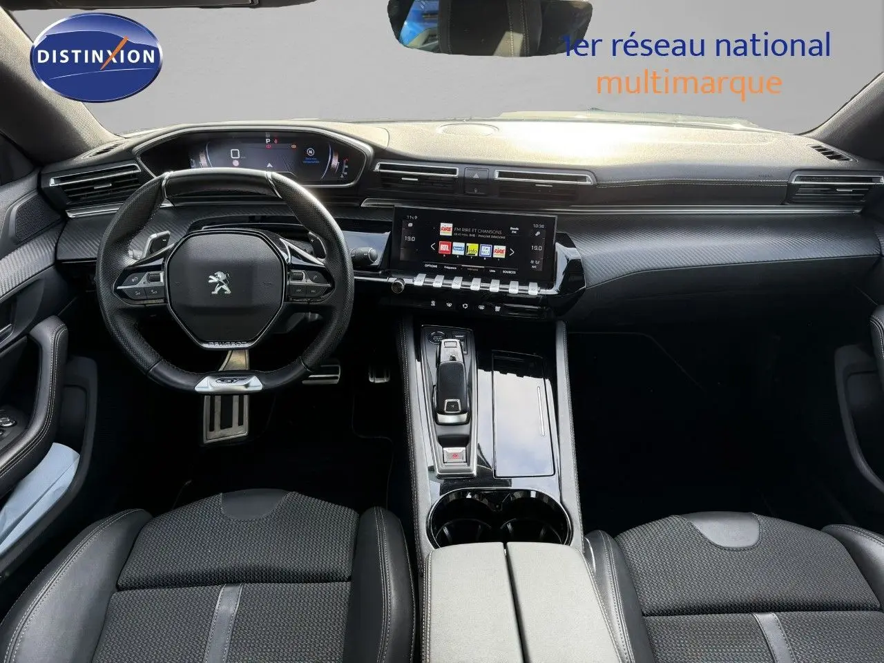 Vue intérieure avant de la Peugeot 508 gris platinium 2023, mettant en valeur le volant compact et l'écran tactile central.