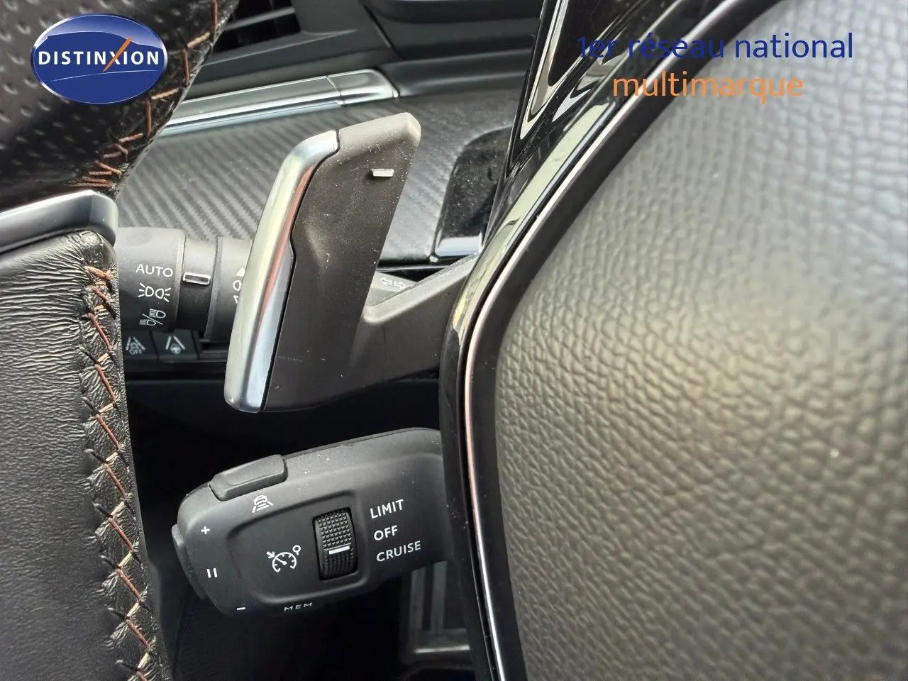 Gros plan sur la commande de régulateur de vitesse au volant cuir noir de la Peugeot 508 gris platinium 2023.