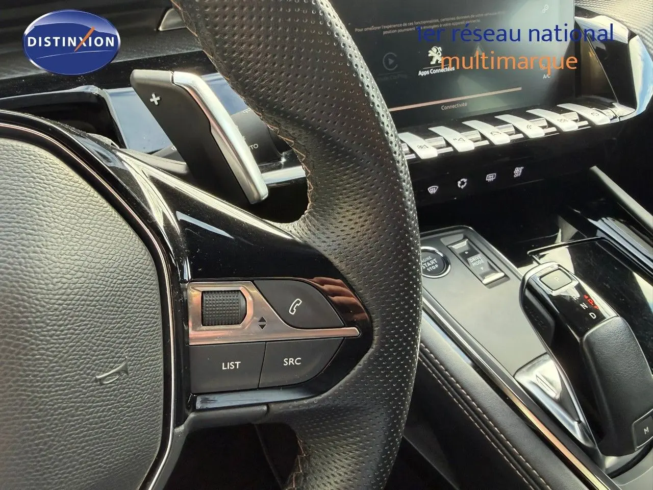Gros plan sur le volant en cuir perforé et la console centrale noire brillante de la Peugeot 508 gris platinium, version 2023.