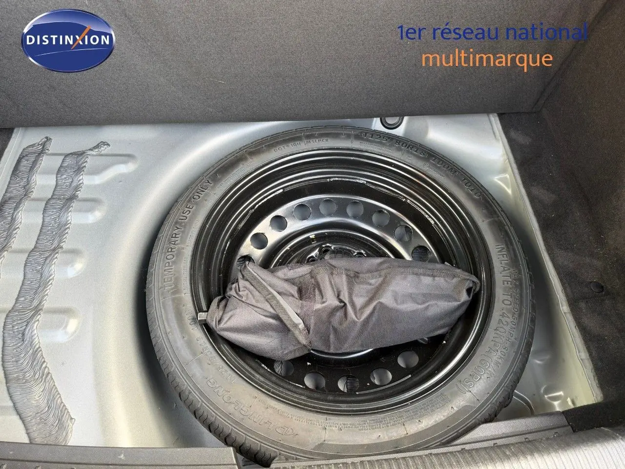 Roue de secours noire dans le coffre d'une Peugeot 508 gris platinium, vue de dessus centrée sur la roue.