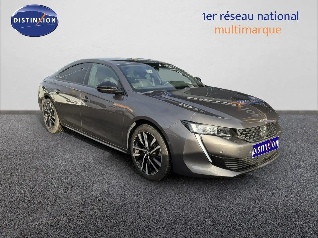 Vue de profil côté gauche d'une Peugeot 508 gris platinium garée devant un showroom avec jantes alliage noires et argentées.