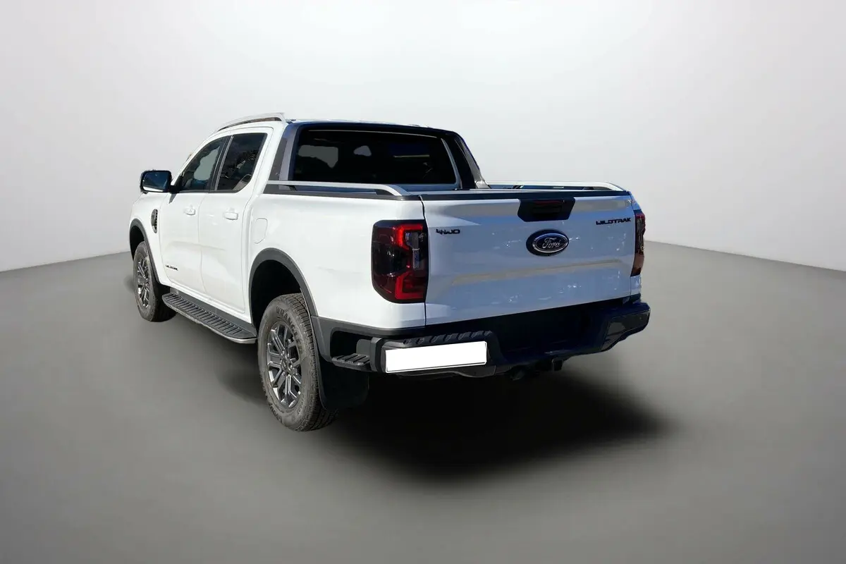 Ford Ranger 2025 blanc glacier en 3/4 arrière droit, avec badges Wildtrak et 4x4 visibles sur la benne.