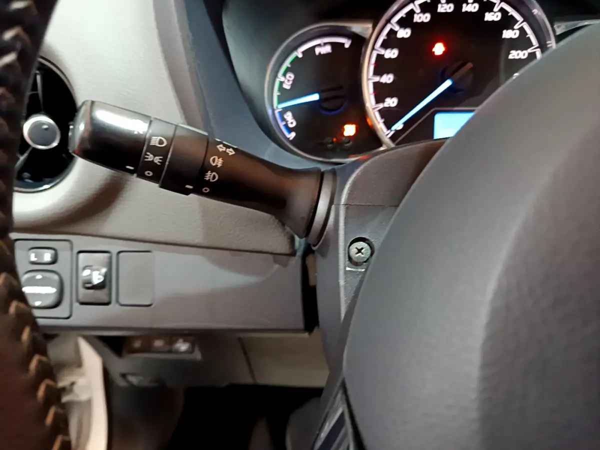 Vue intérieure centrée sur le commodo gauche et le tableau de bord éclairé de la Toyota Yaris hybride 2020.