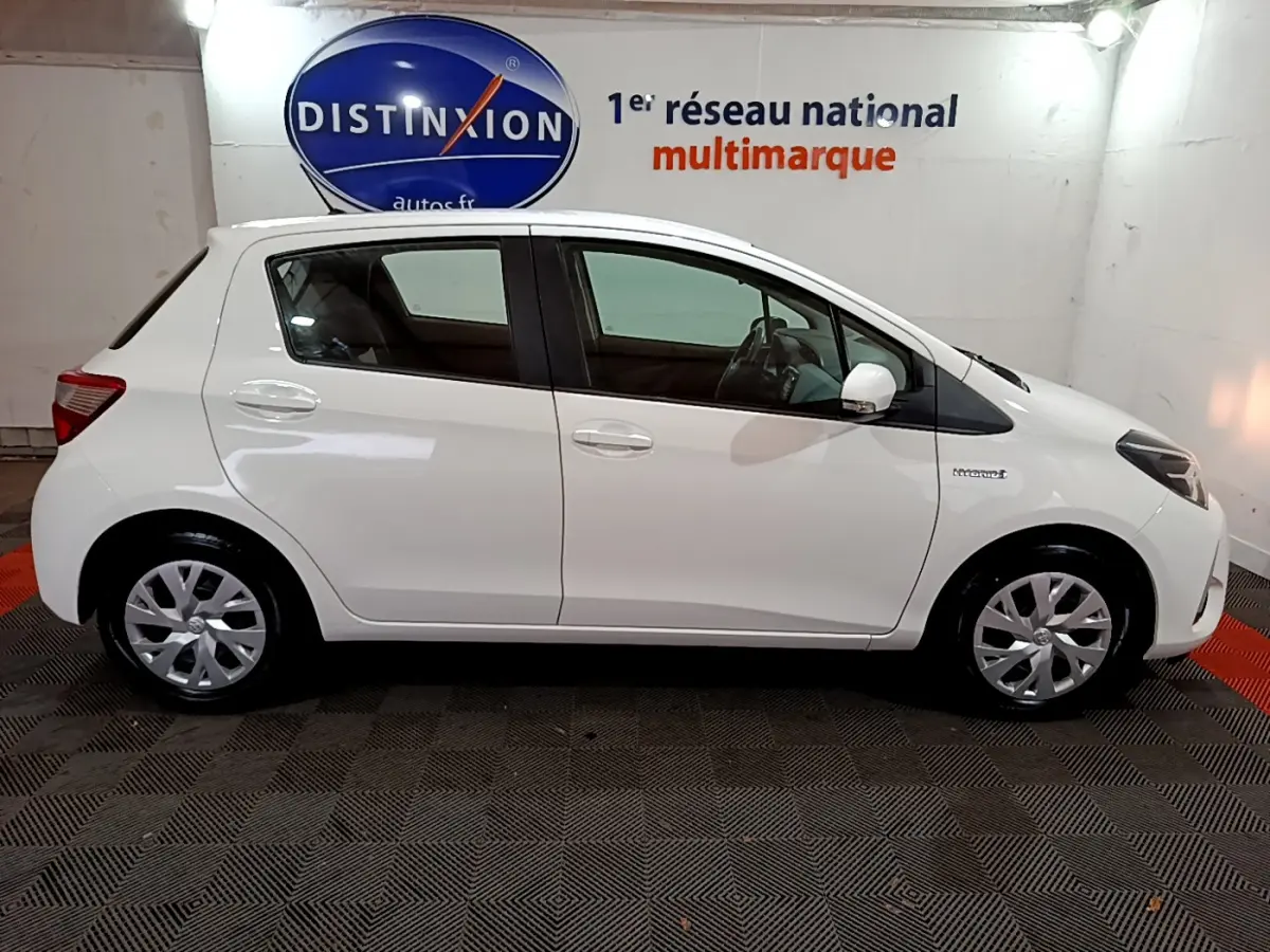 Profil droit de la Toyota Yaris 1.5 Hybride blanche de 2020, avec logo hybride visible sur l'aile avant.