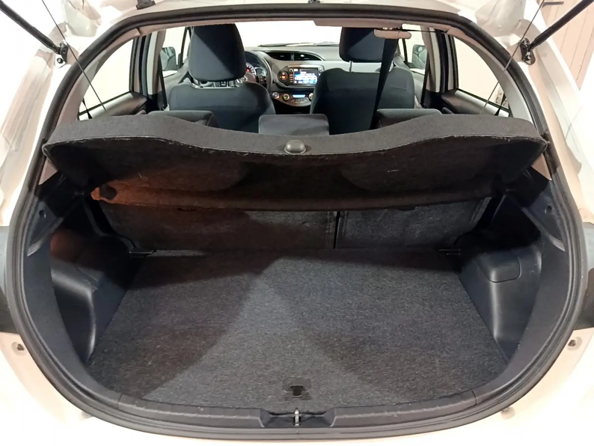 Vue arrière du coffre ouvert d'une Toyota Yaris blanche, montrant l'espace de chargement et l'intérieur des sièges avant.