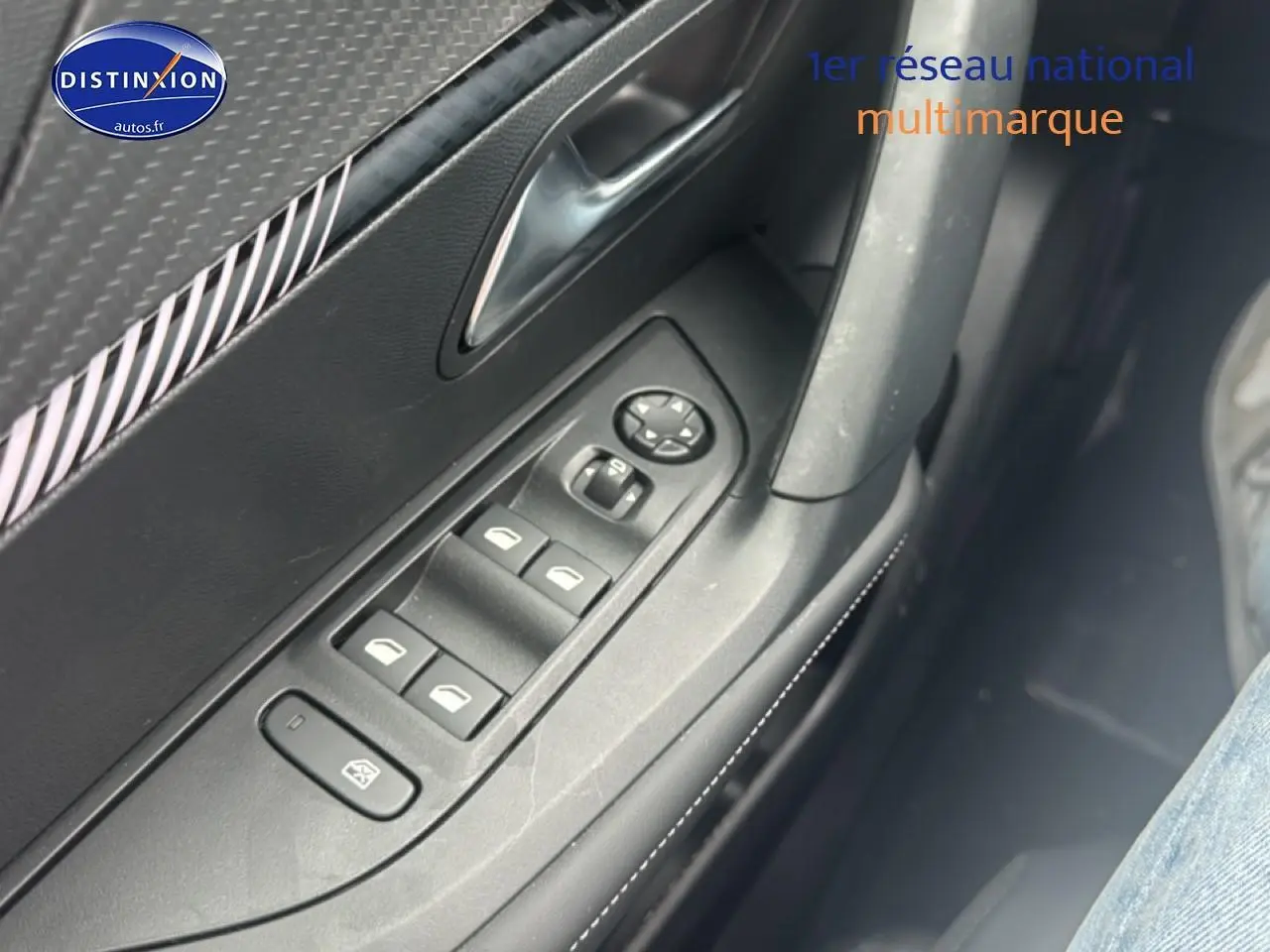 Vue rapprochée des commandes de vitres électriques et rétroviseurs sur la porte côté conducteur d’un Peugeot 2008 gris.