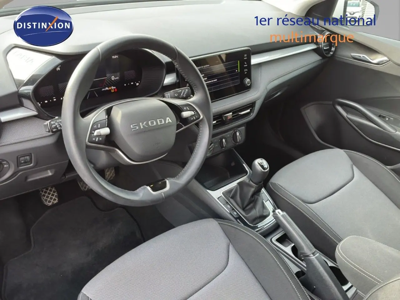 Vue intérieure de face de la Skoda Fabia 2025, montrant le volant multifonction, la console centrale et les sièges tissu gris.