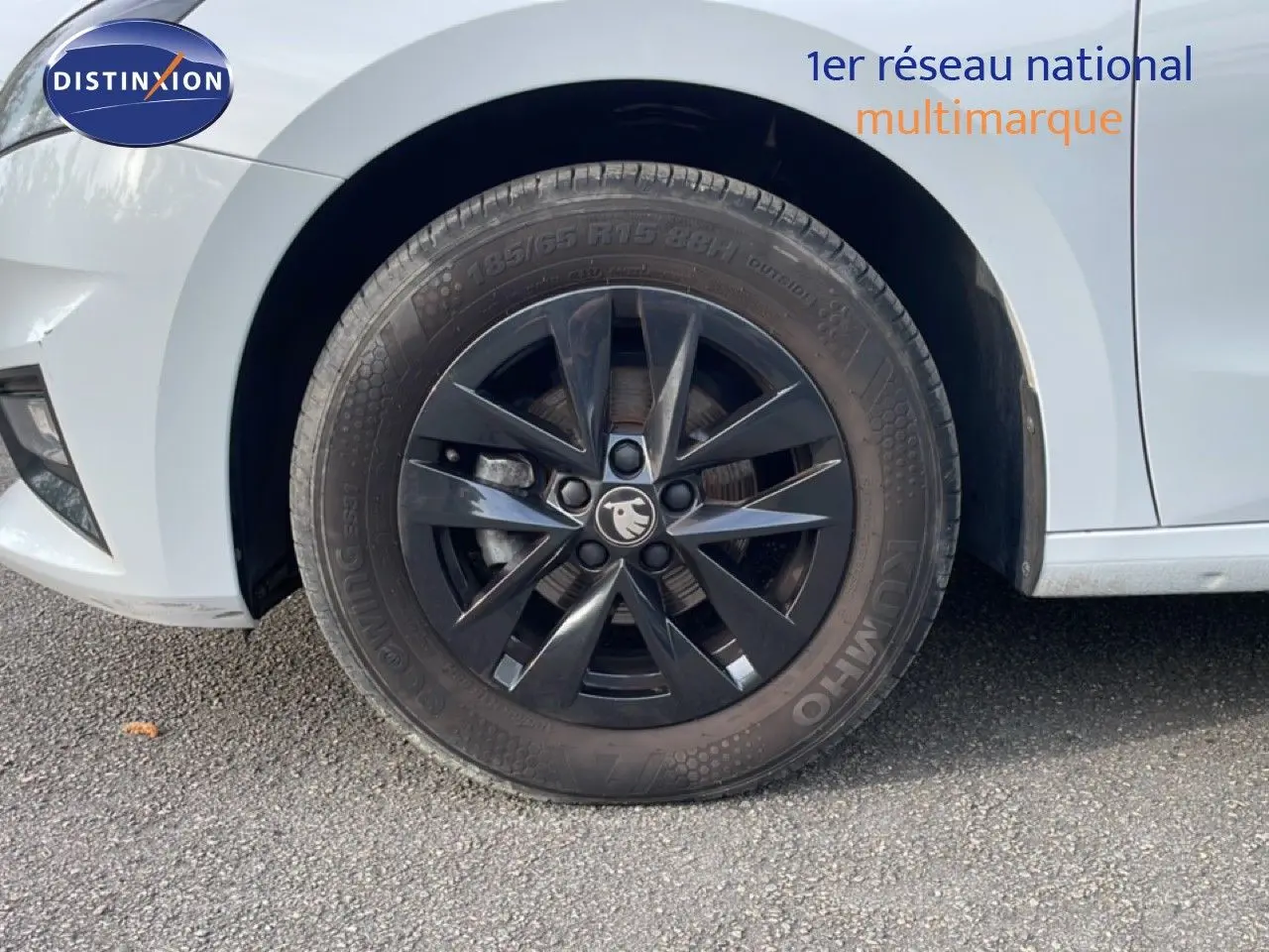 Gros plan sur la roue avant gauche noire d'une Skoda Fabia blanc glacier, mettant en valeur la jante 15 pouces au design moderne.