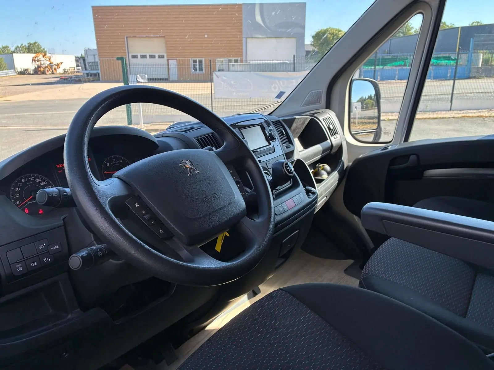 Vue intérieure côté conducteur du Peugeot Boxer cabine approfondie 2019, tableau de bord noir avec volant multifonction.