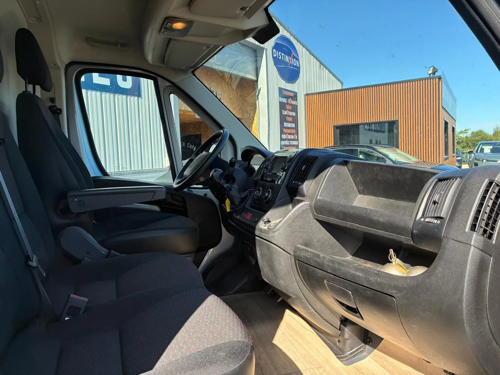 Vue intérieure côté conducteur du Peugeot Boxer cabine approfondie 2019, avec tableau de bord noir et sièges en tissu gris.