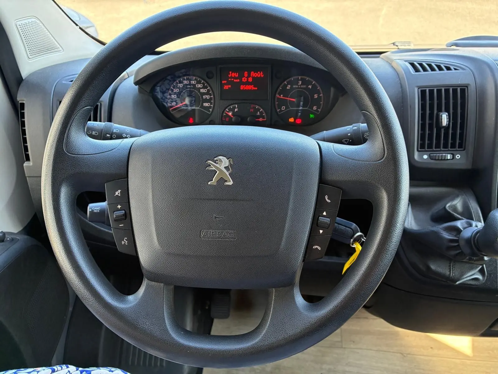 Vue rapprochée du volant noir de la Peugeot Boxer 2.2 BlueHDi 165 2019 avec tableau de bord et levier de vitesses manuel.