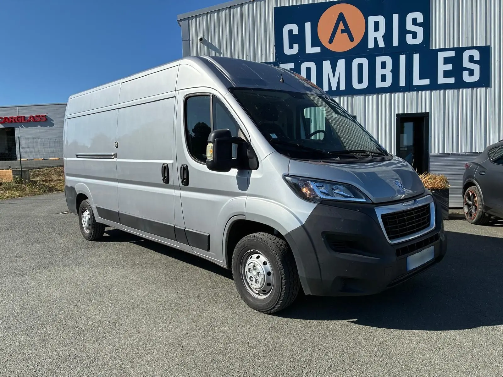 Vue 3/4 avant droit d’un Peugeot Boxer cabine approfondie gris 2019, avec calandre noire et pare-chocs foncé.
