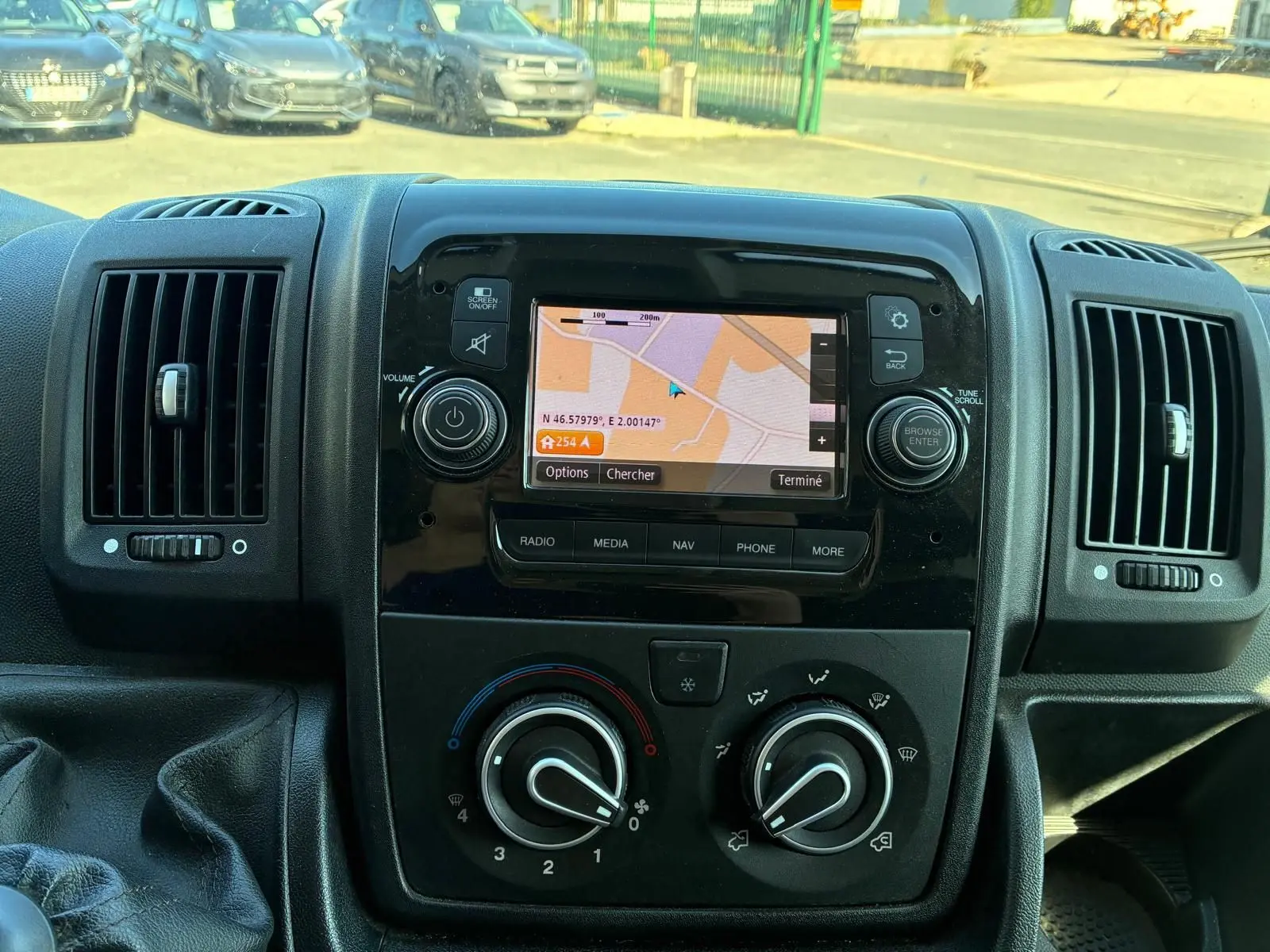 Vue rapprochée du tableau de bord noir du Peugeot Boxer cabine approfondie 2019 avec écran GPS allumé et commandes de climatisation.